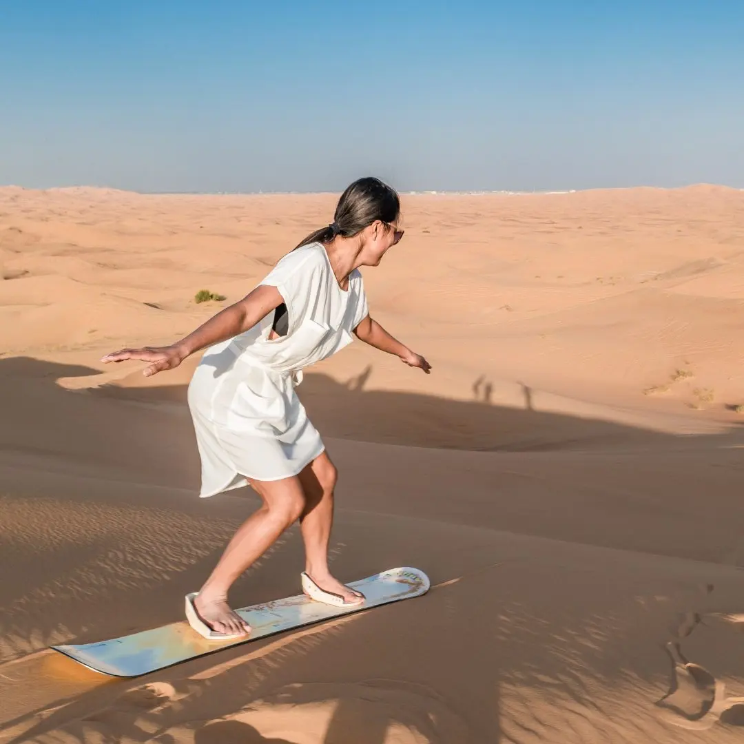 Sandboarding down a dune on the desert safari