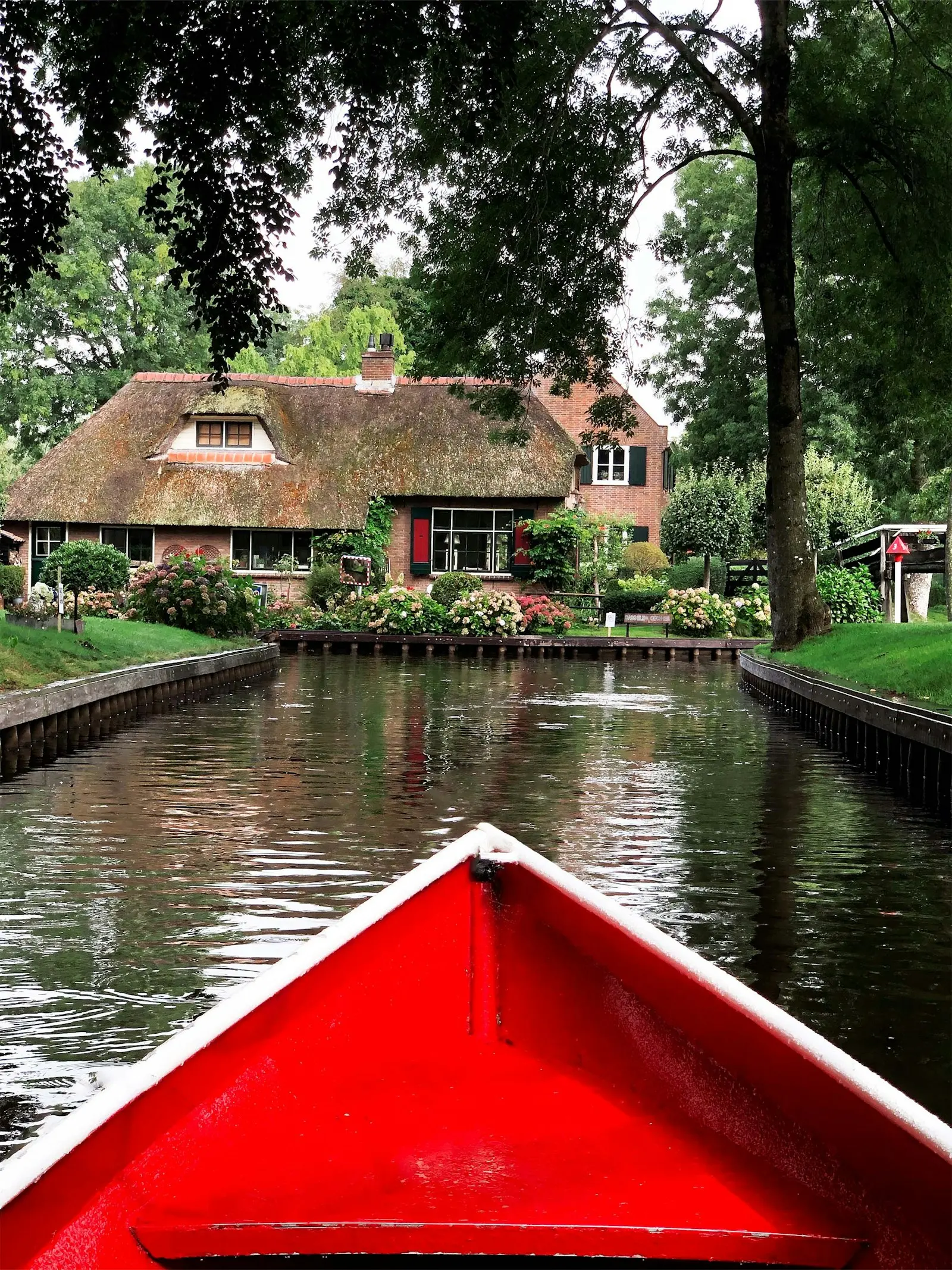 A thatched farmhouse and moored boats on a canal in Giethoorn